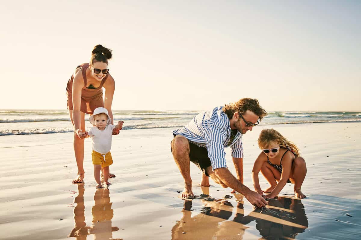 mum, dad and 2 children playing on a beach